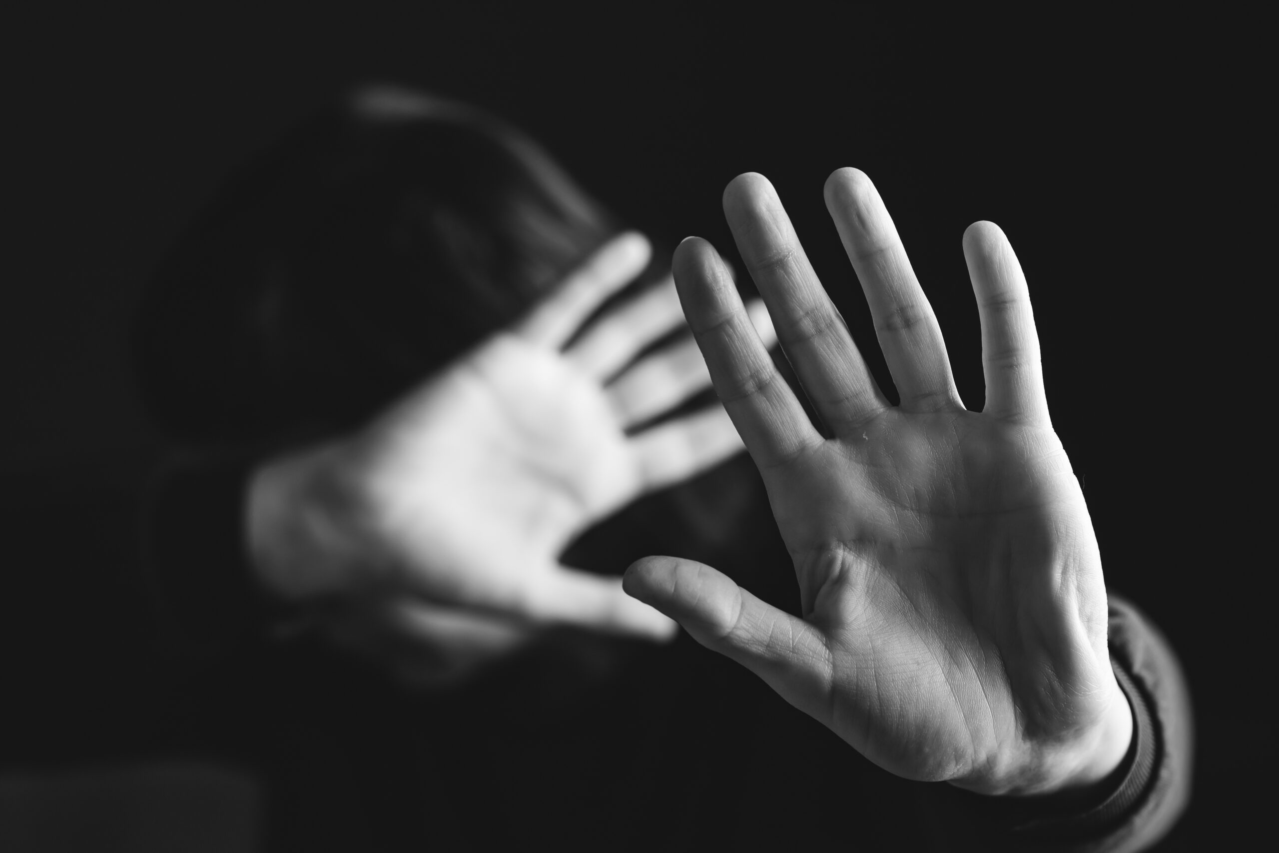 person with hands up blocking their face