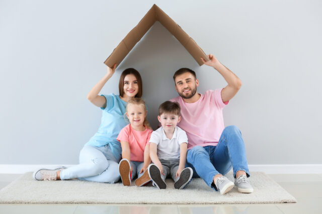 parents with children under cardboard house box