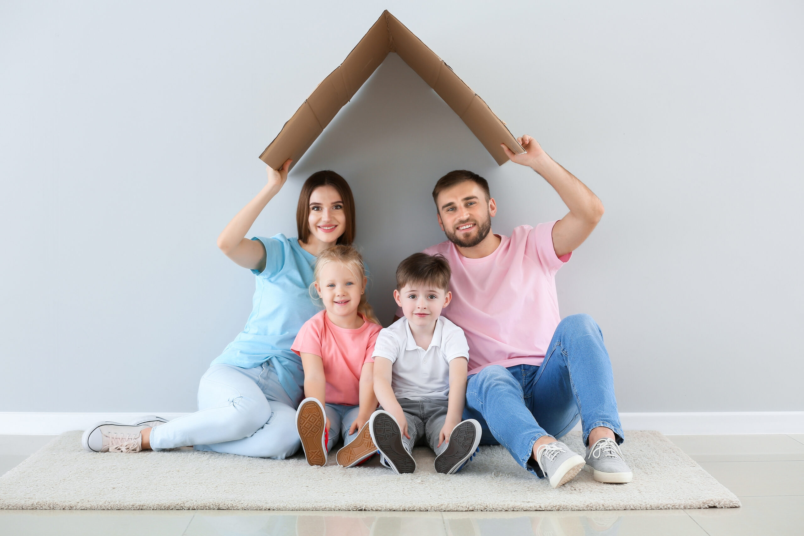 parents with children under cardboard house box
