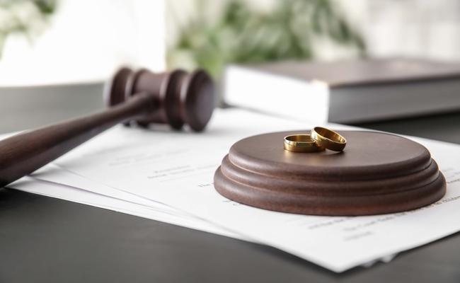A judges gavel beside a sound block with 2 abandoned wedding rings atop; Suffolk County Post-Judgment Attorney concept image