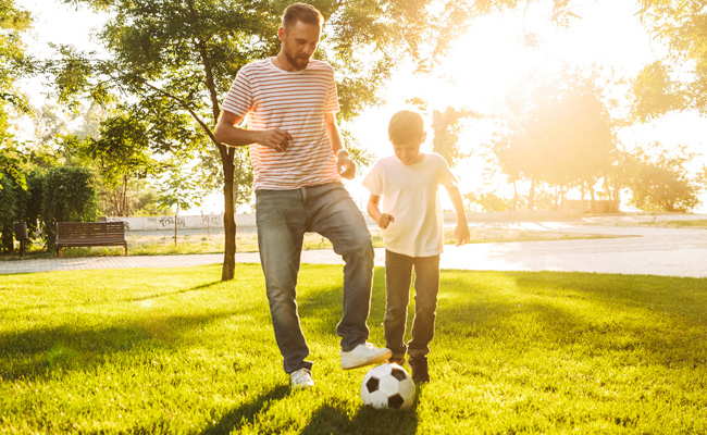 father and son playing soccer in the sunlight