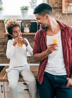 father and daughter in kitchen drinking juice