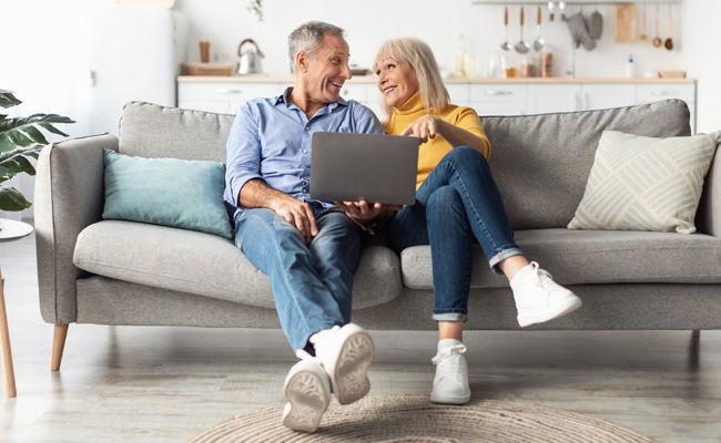 senior couple sitting on couch looking at laptop