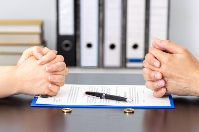 Hands of wife and husband signing divorce documents